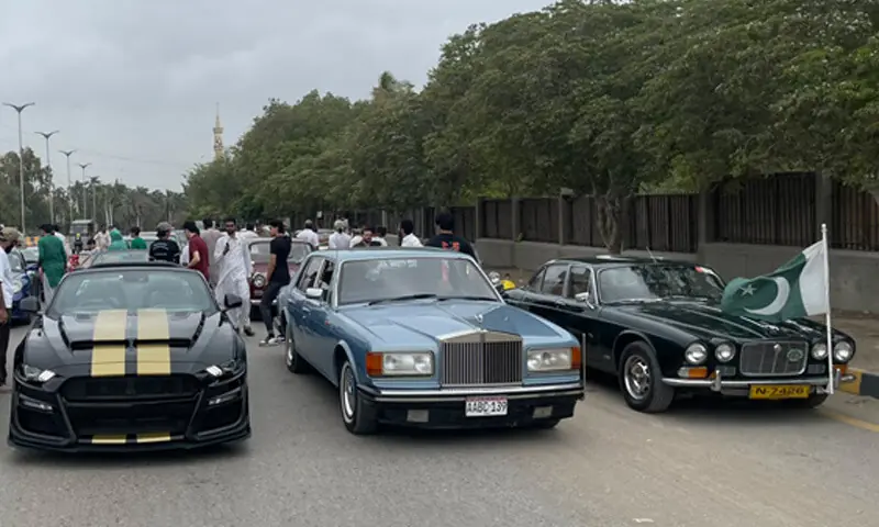 Classic cars bearing national flags drive through Karachi's streets